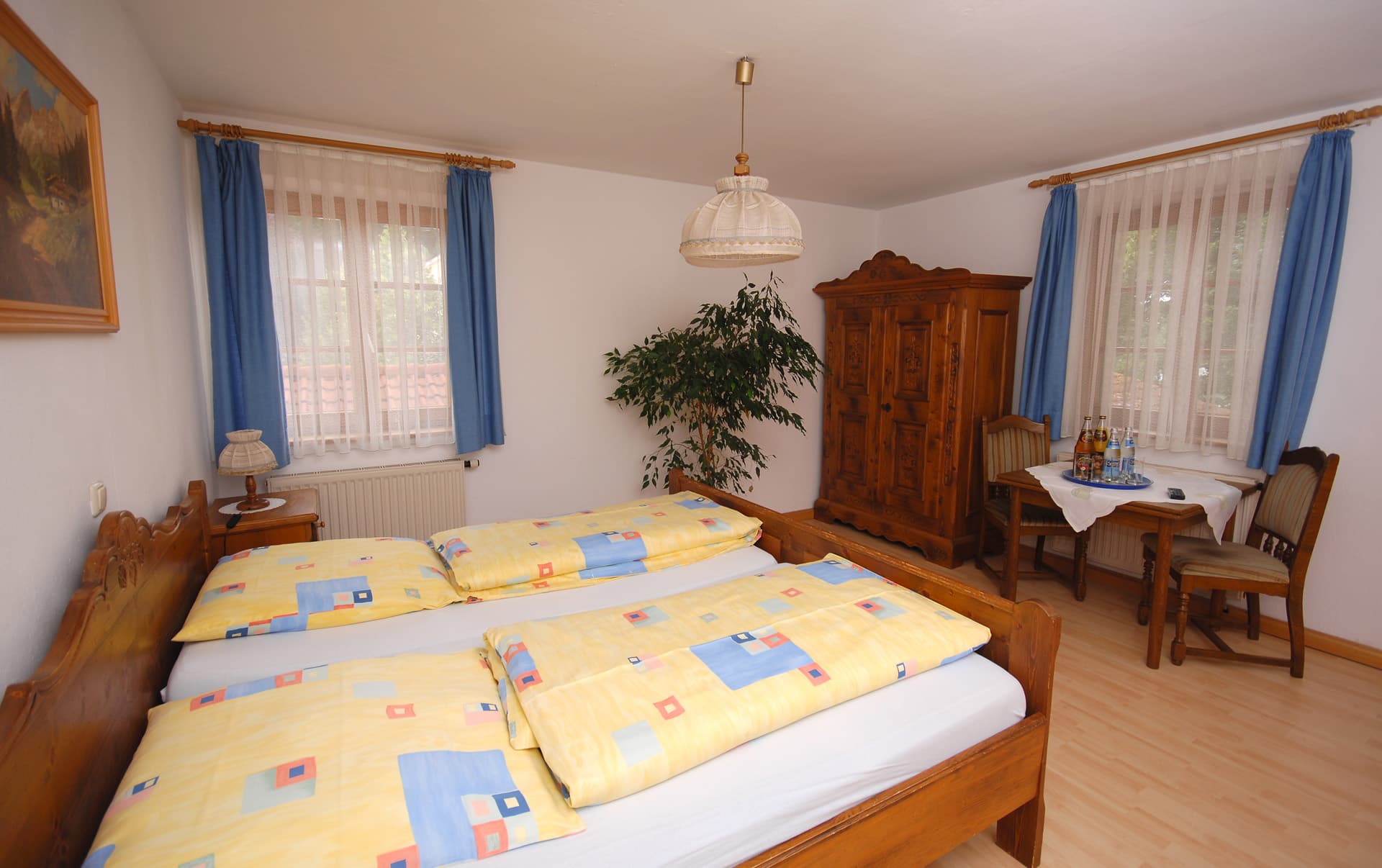 Gästezimmer mit zwei Betten und blauen Vorhängen