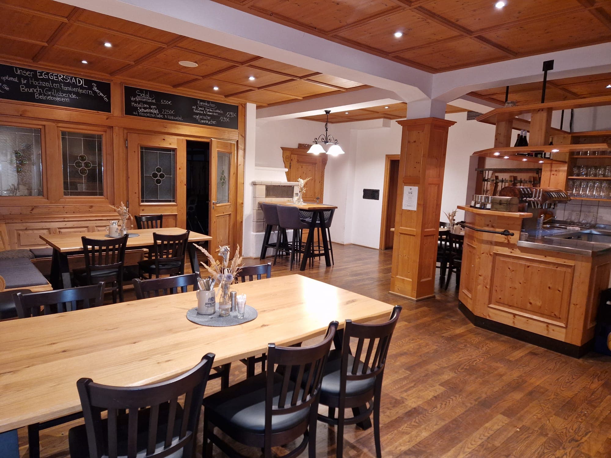 Gaststube mit Holztischen, Theke und warmem Licht