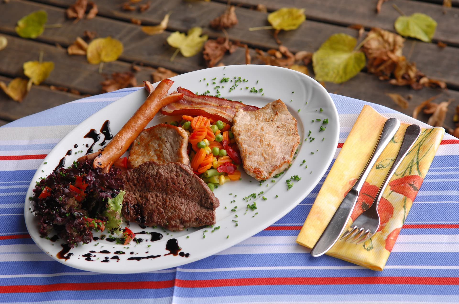 Fleischgericht mit Gemüse, angerichtet zwischen Herbstlaub