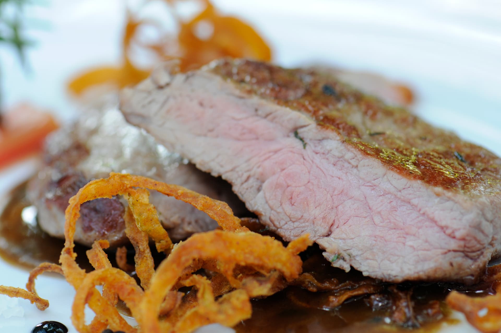 Rosa gebratenes Rindersteak mit Röstzwiebelringen
